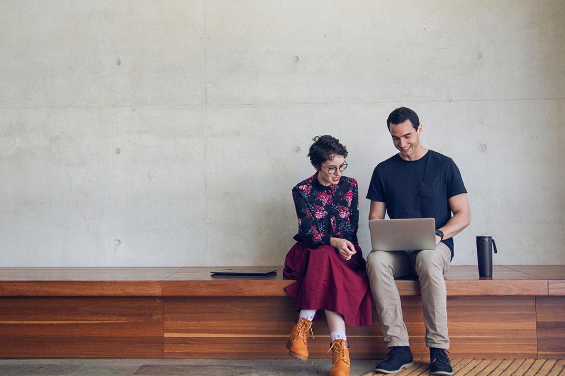 Two students sitting looking at a laptop